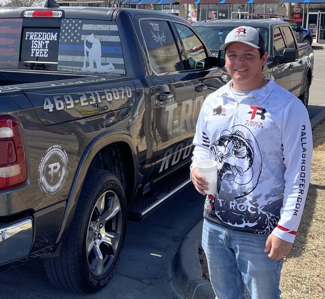 Man smiling holding drink while standing next to his truck